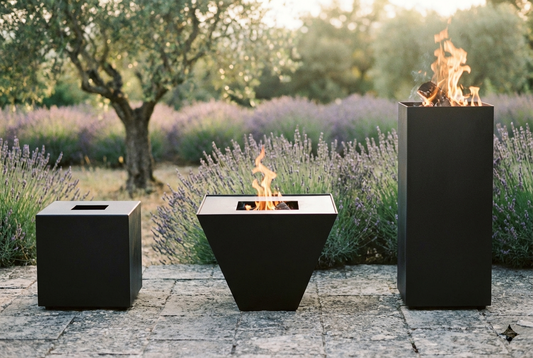 Meilleur brasero 2026 : trois braseros en acier noir sur terrasse provençale au coucher du soleil, comparatif des meilleurs modèles